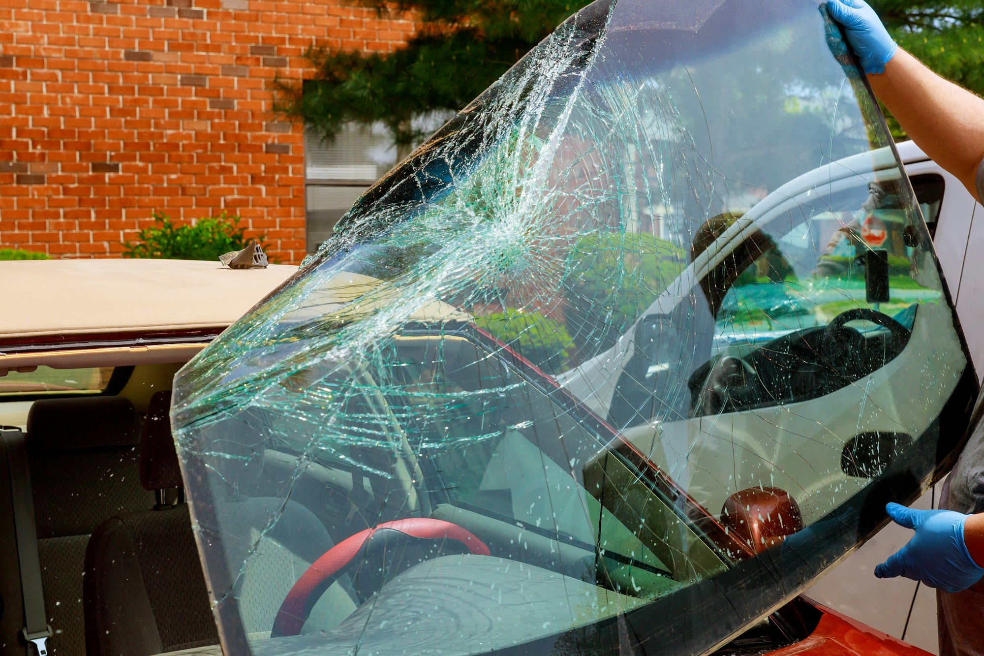 Broken windshield car special workers take of windshield of a car in auto service from inside from