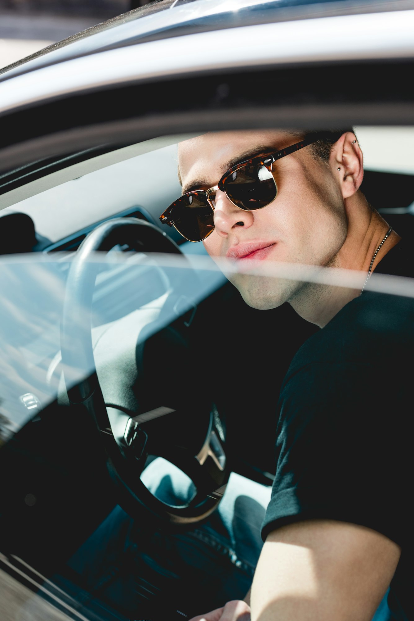 selective focus of handsome stylish man in sunglasses posing in car